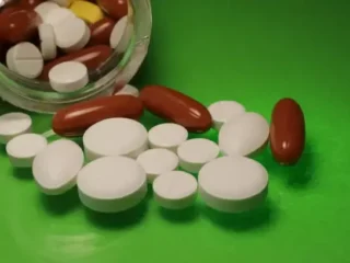 imgi_6_white-pills-and-capsules-on-a-green-background-near-a-plastic-bottle