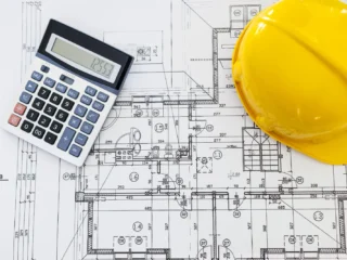 close-up-of-house-blueprints-with-yellow-helmet-2023-11-27-04-49-46-utc-scaled-1