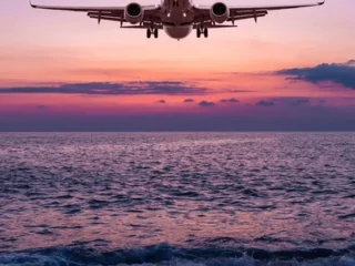 passenger-airliner-landing-over-ocean-600nw-2699173869-2